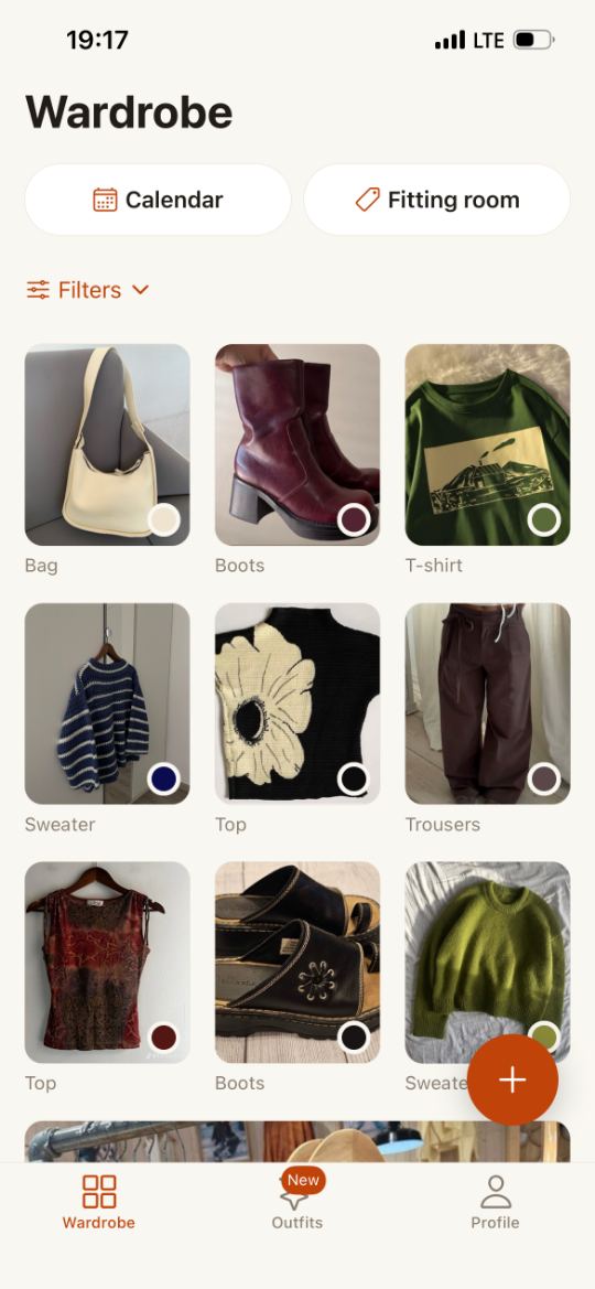 Ecru’s wardrobe on an iPhone: a “Wardrobe” heading, calendar and fitting-room buttons, and below them a grid of items — a bag, boots, a T-shirt, a jumper — each with a dot in its own colour.